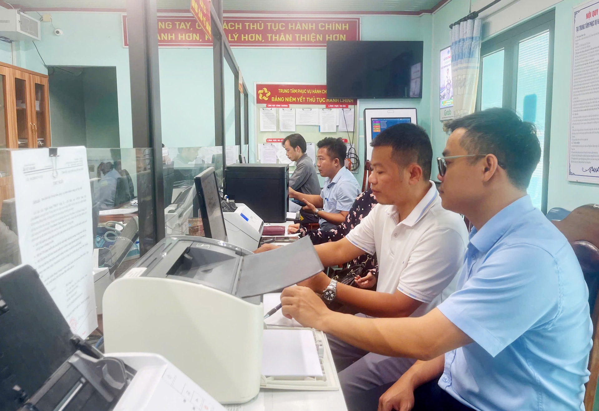 Anh Phan Văn Minh (ngoài cùng bên phải) hướng dẫn công dân thực hiện thủ tục hành chính trên Cổng dịch vụ công trực tuyến