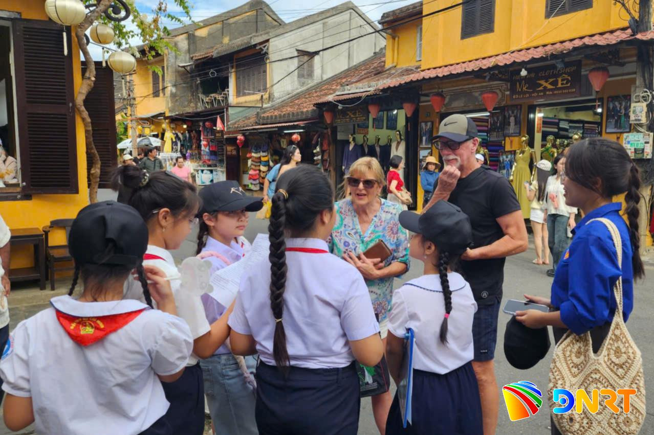 Em Phan Quỳnh Như (thứ ba từ phải sang) tự tin giao tiếp bằng tiếng Anh với một nhóm du khách nước ngoài tại phố cổ Hội An. Ảnh: THU HƯƠNG