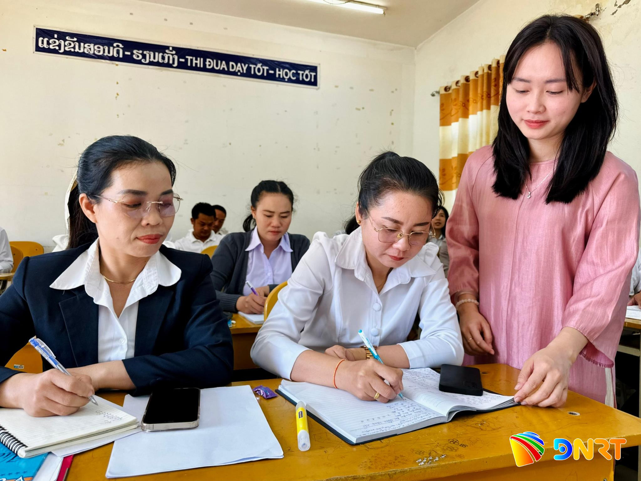Cô giáo Doãn Thị Bảo An (bên phải) hướng dẫn học viên viết tiếng Việt tại Trung tâm Tiếng Việt tỉnh Savannakhet (ảnh chụp vào tháng 3/2026). Ảnh: ALĂNG NGƯỚC