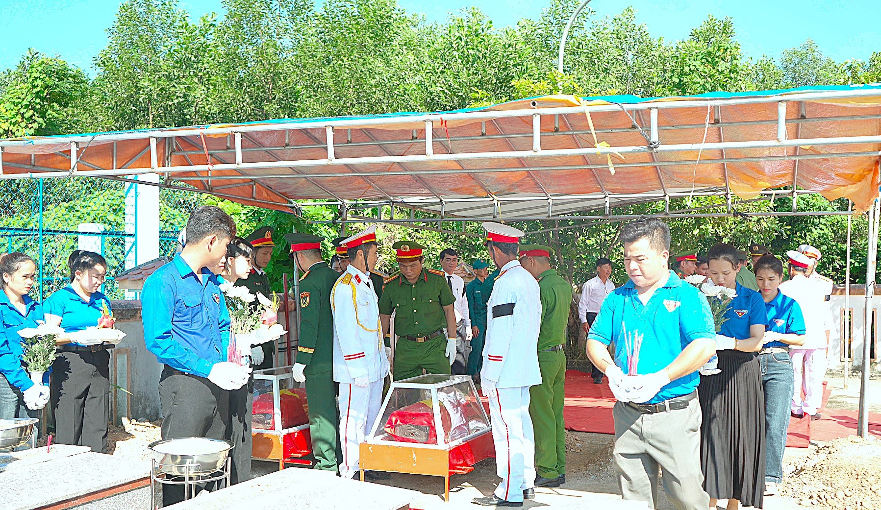 Thực hiện nghi thức an táng hài cốt liệt sĩ tại nghĩa trang xã Quế Phước. Ảnh: MINH THÔNG